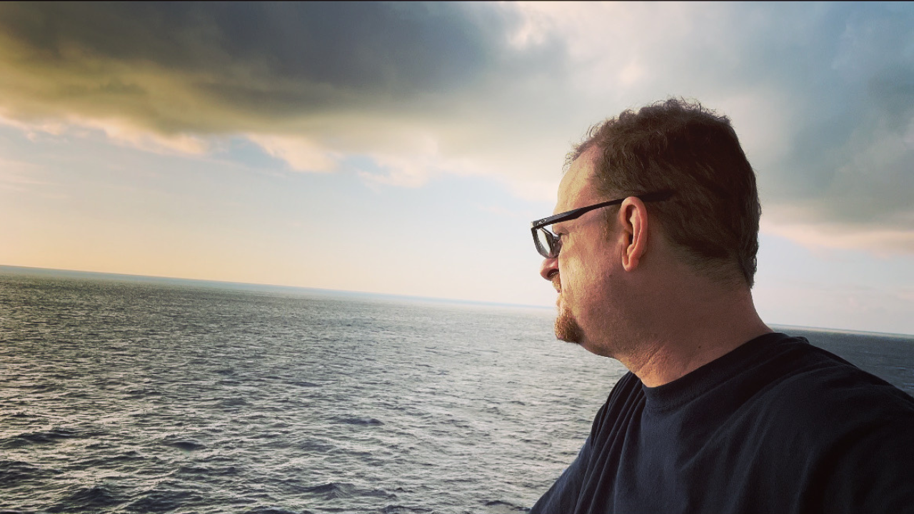 Paul Milakeve looking out over the ocean at sunset